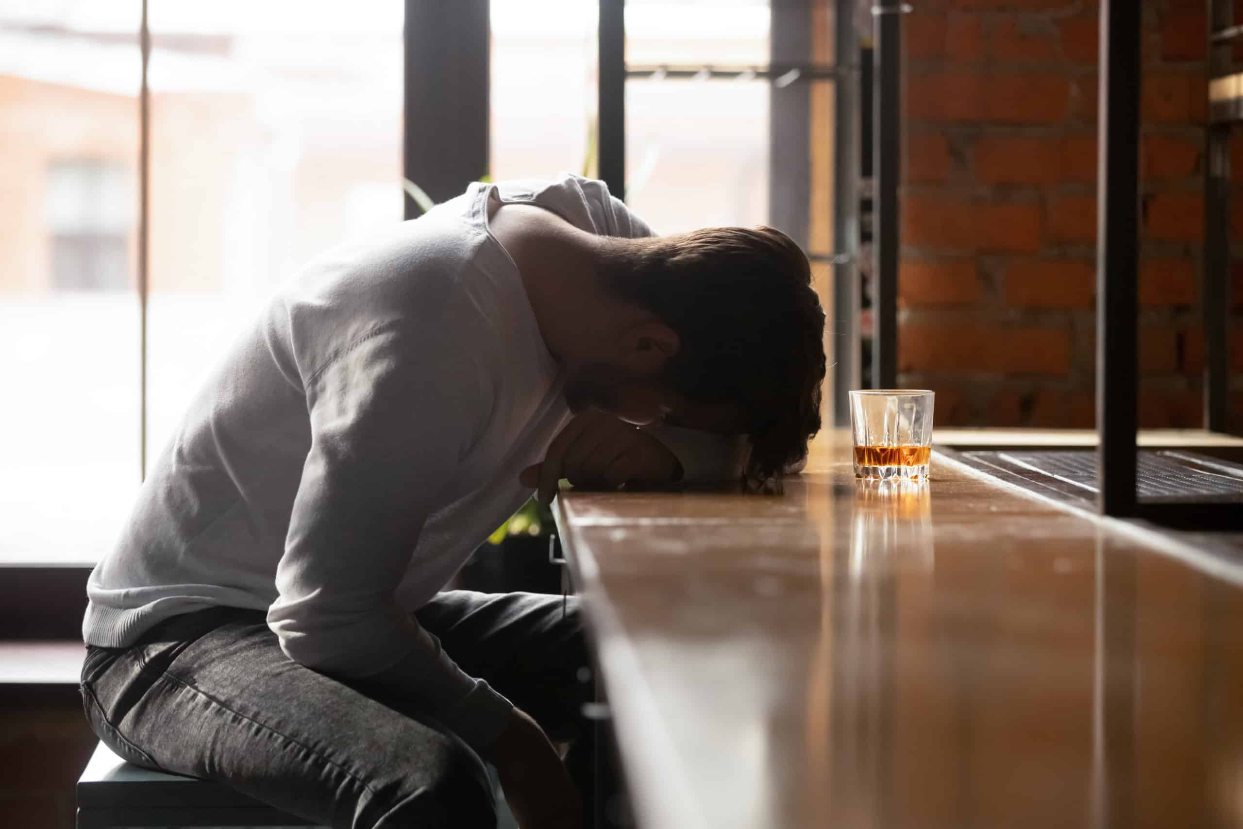 Depressed young man addicted to drinking who is sleeping alone in the bar.
