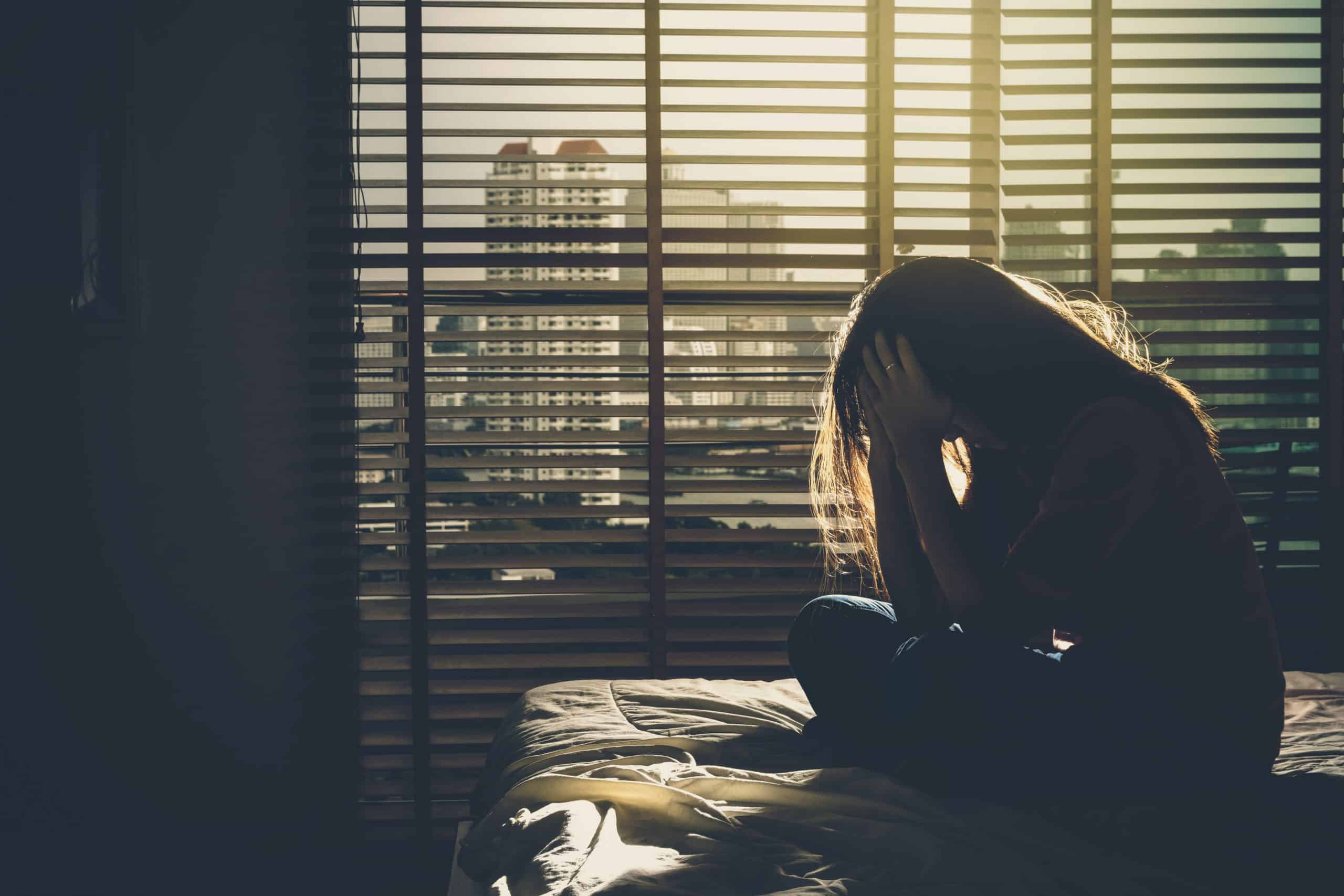 Depressed woman sitting Alone On The Bed With Hands