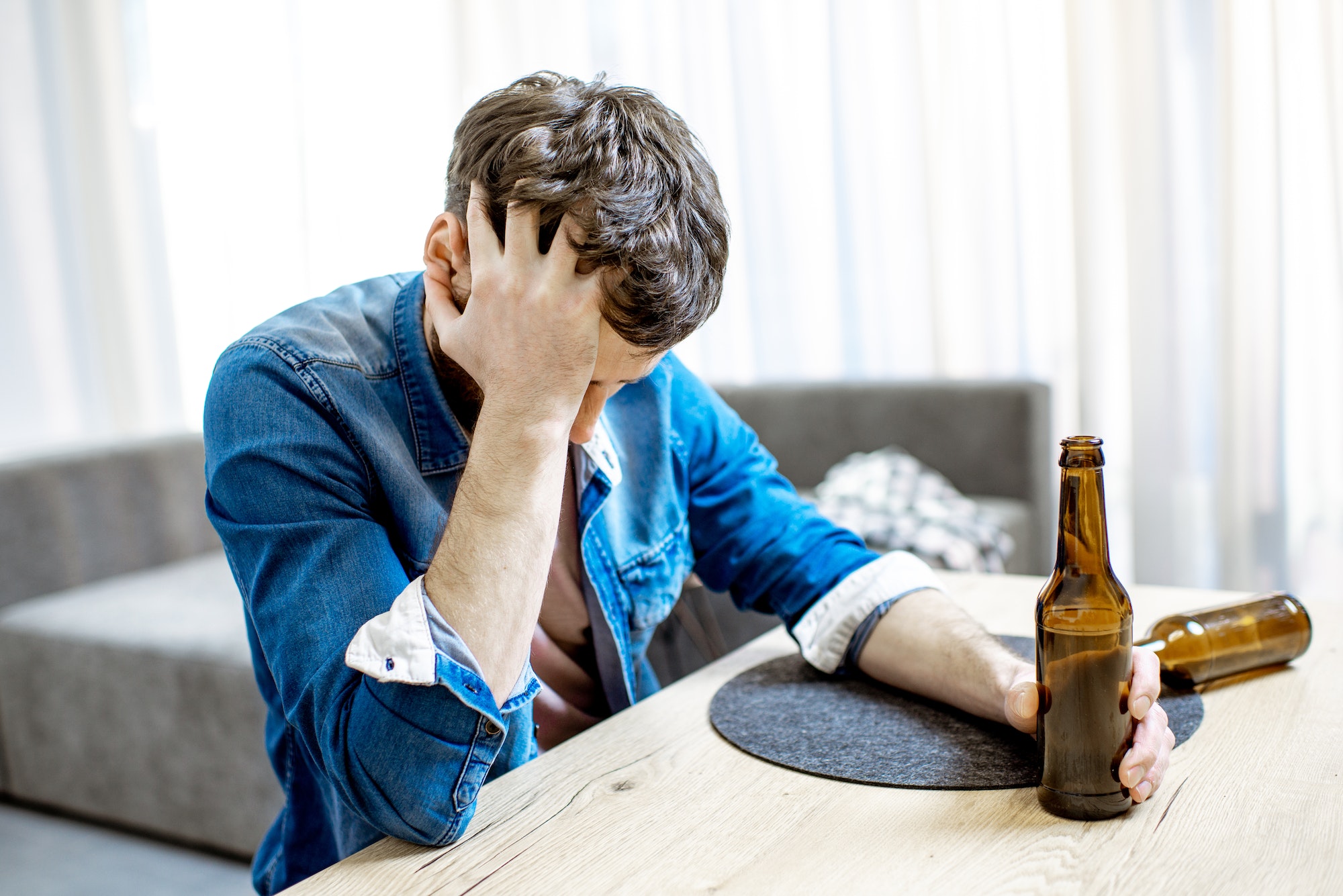 Drunk male alcoholic with drinks at home