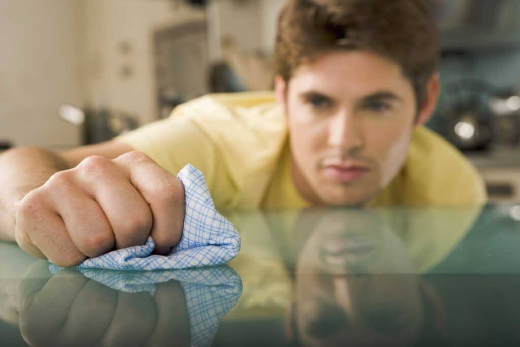Man dealing with OCD is cleaning glass table very thoroughly