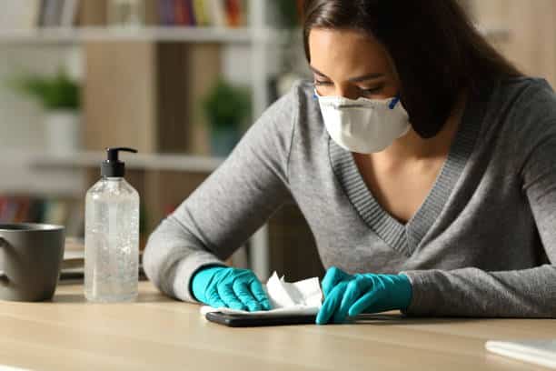 Lady diagnosed with Obsessive Compulsive Disorder cleaning dinner table thoroughly with mask put on.
