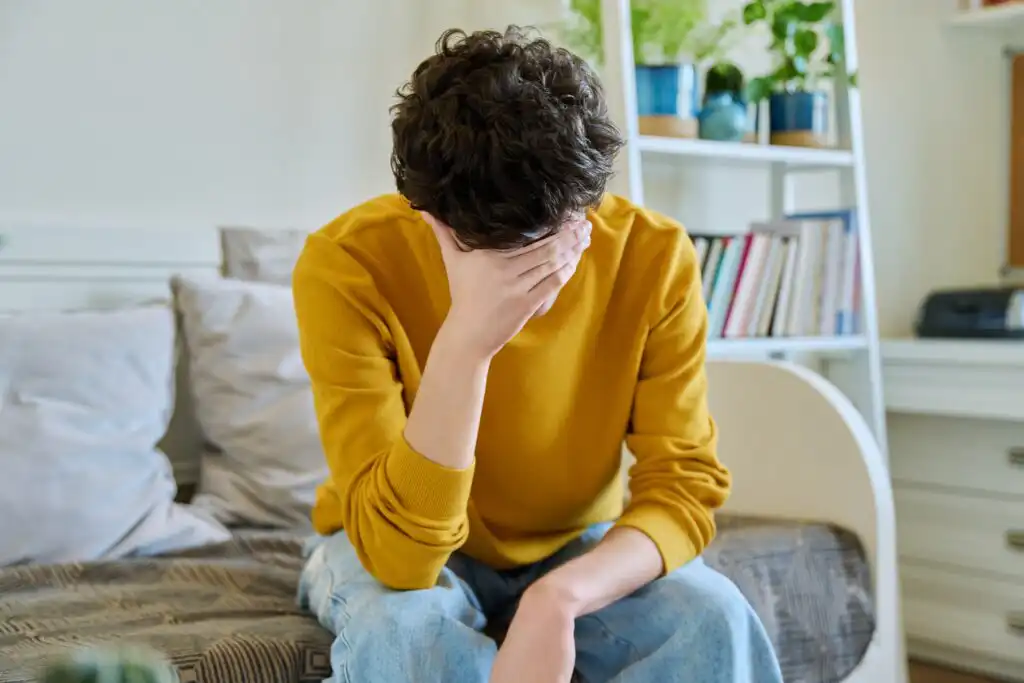 Sad,Upset,Young,Man,Sitting,On,Couch,At,Home,,Touching