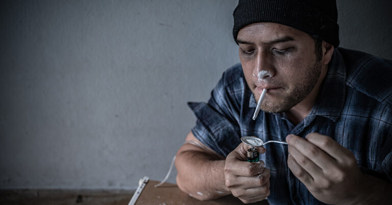 Person handling cocaine in a dimly lit setting, used to illustrate factors affecting cocaine metabolism, elimination, and detection times.